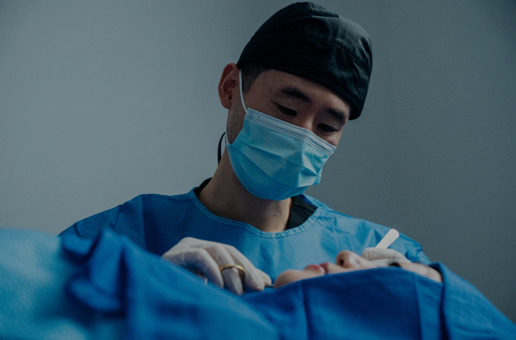 Harry Ching MD and mask performing medical procedure in operating room
