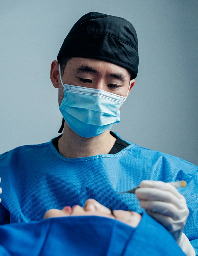 Harry Ching MD in blue scrubs and mask preforming surgery in a operation room - Asian Rhinoplasty in Las Vegas, NV