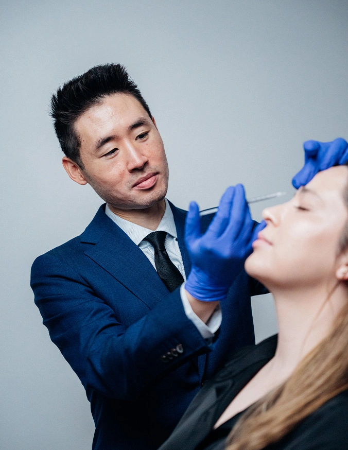 Harry Ching MD in blue suit administering facial injection to female patient wearing medical gloves - Botox & Wrinkle Relaxers in Las Vegas, NV