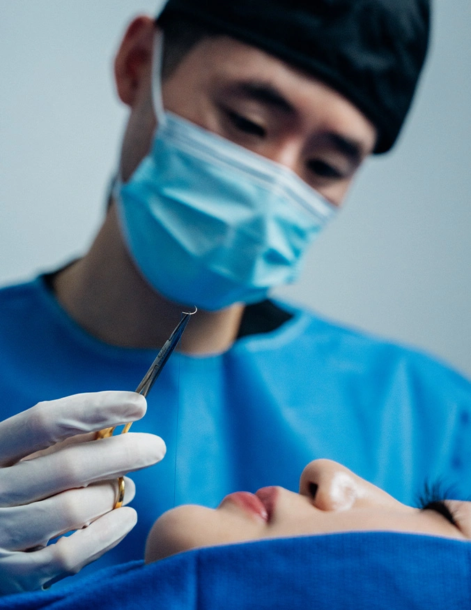 Harry Ching MD in blue scrubs and mask performing surgery on a patient - Lip Lift in Las Vegas, NV
