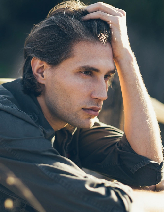 Young man with hand in hair wearing black shirt in natural outdoor lighting - Male Facial Rejuvenation in Las Vegas, NV