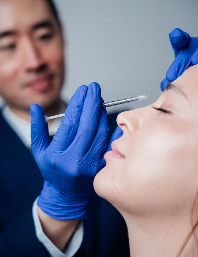 Harry Ching MD in blue gloves performing facial cosmetic injection procedure on female patient - Non-Surgical Rhinoplasty in Las Vegas, NV