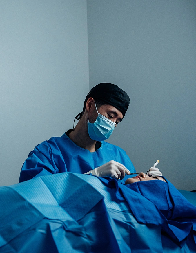 Harry Ching MD in blue scrubs and mask performing medical procedure in sterile operating room environment - Revision Rhinoplasty in Las Vegas, NV
