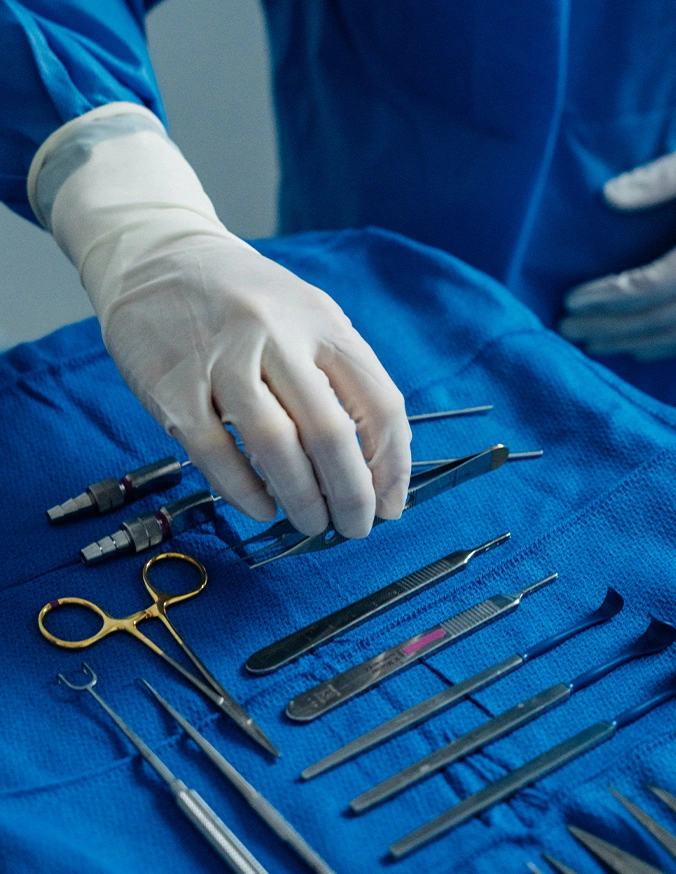 Harry Ching MD reaching for surgical instruments arranged on blue sterile drape in operating room - Scar Revision or Dermabrasion in Las Vegas, NV