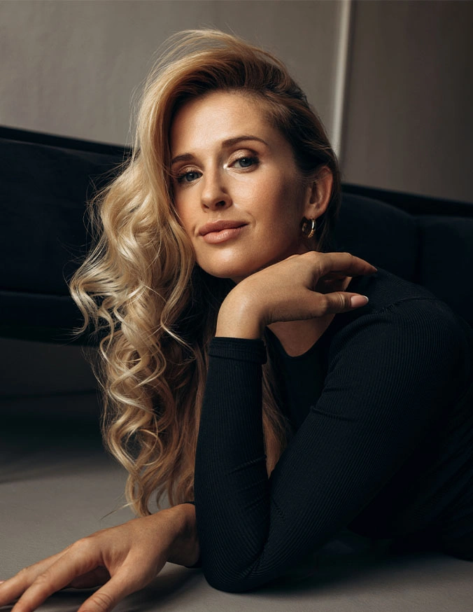 Elegant blonde woman with wavy hair in black outfit posing thoughtfully in professional portrait photography - Upper Eyelid Surgery in Las Vegas, NV