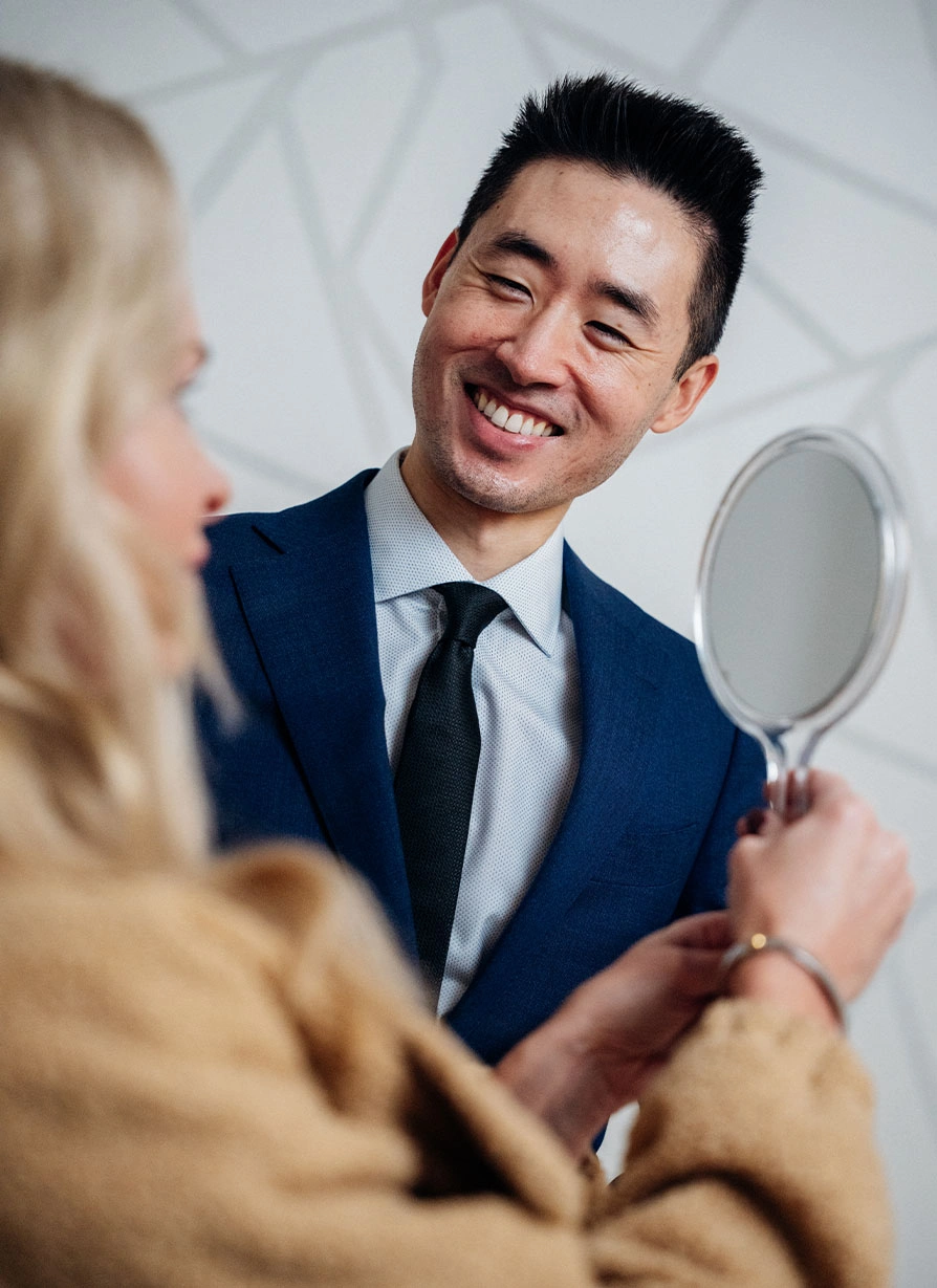 Harry Ching MD showing patient their face in handheld mirror during consultation