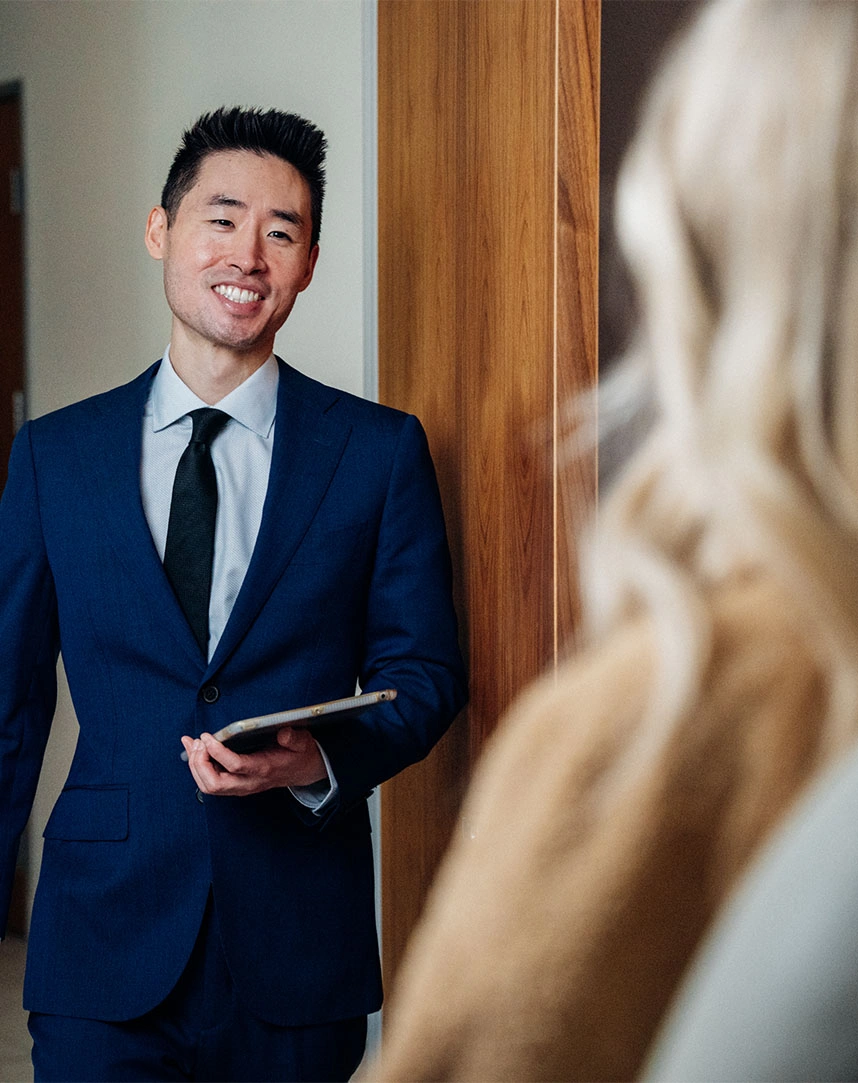 Harry Ching MD in suit discussing treatment options with patient in medical office